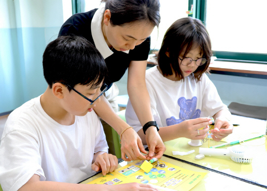 ▲ 27일 일일 선생님이 된 LG화학 임직원이 아이들과 폐플라스틱으로 키링 만들기를 체험을 하고 있다. ⓒLG화학