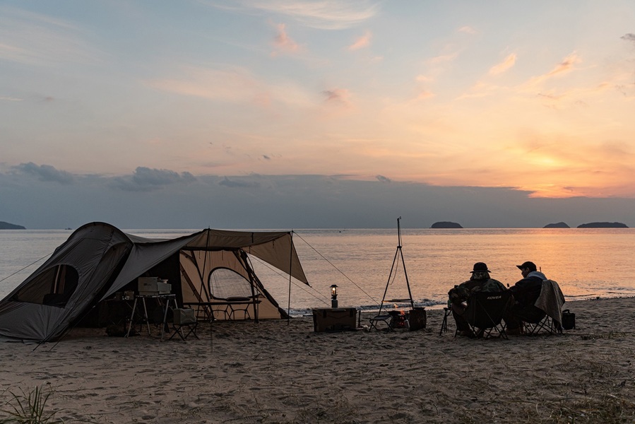 ▲ 바닷가 바람을 맞으며 펼쳐진 ㈜코베아의 야외용 텐트 아래, 두명의 캠퍼가 서로의 이야기와 웃음을 나누는 낭만 가득한 순간. 끝없이 펼쳐진 푸른 바다와 부드러운 모래 위에서 자유와 여유를 만끽하는 그들의 캠핑 라이프가 고스란히 담겨 있다.ⓒ㈜코베아
