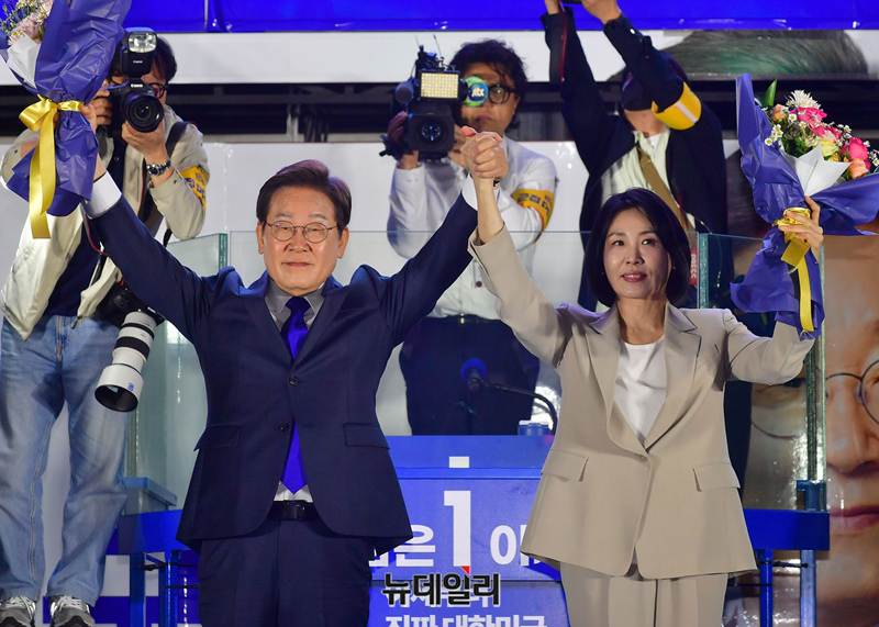 ▲ 더불어민주당 이재명 대선 후보와 부인 김혜경 여사가 4일 서울 여의도 국회 인근에서 당 주최로 열린 국민개표방송 행사에 참석해 꽃다발을 받은 뒤 시민들을 향해 두 팔을 들어 인사하고 있다.ⓒ 이종현 기자