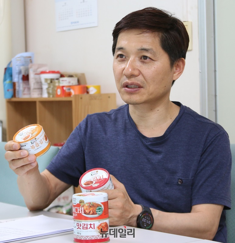 ▲ ㈜시즈너 김주옥 이사가 자체 브랜드로 생산한 복음김치와 맛김치 캔을 자랑하고 있다.ⓒ이길표 기자