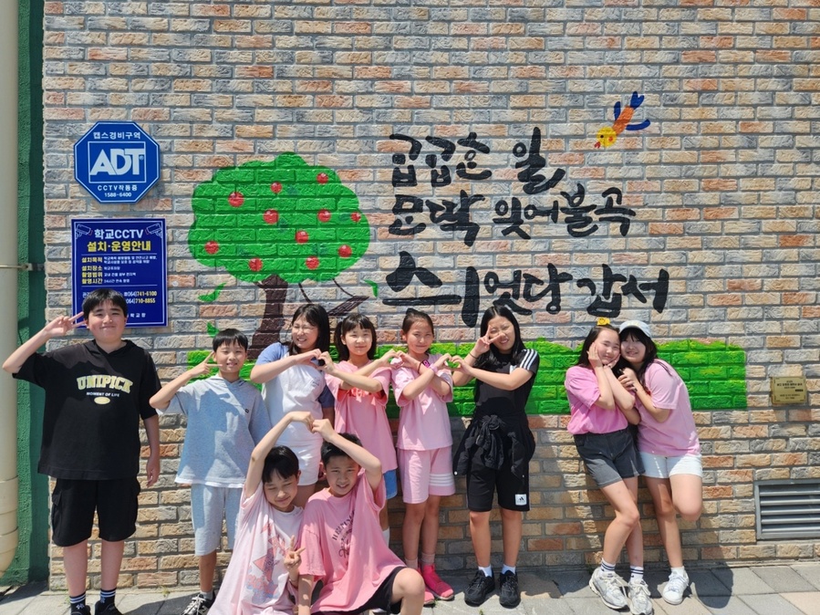 ▲ 신제주초등학교 학생들이 학교 외벽에 아로새겨진 제주어 벽화 앞에서 사진을 찍고 있다. ⓒ제주특별자치도교육청 제공