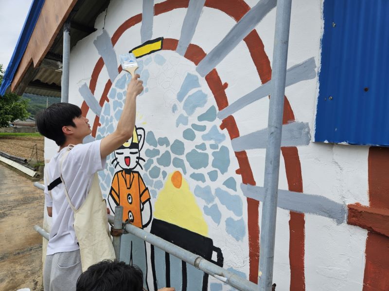 ▲ 충남 보령군 청라면 일대에서 ‘하계 기술봉사 활동’에 나선 한기대 학생이 마을 벽화를 그리고 있다.ⓒ한기대