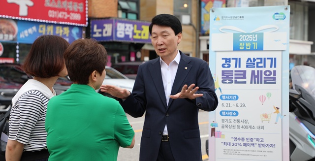 ▲ 김민철 경기도시장상권진흥원 원장이 '2025년 상반기 경기 살리기 통큰 세일'에 참여하고 있는 안양 삼막 맛거리촌 상인회를 찾아 시민들에게 행사를 설명하고 있다. ⓒ경기도시장상권진흥원 제공