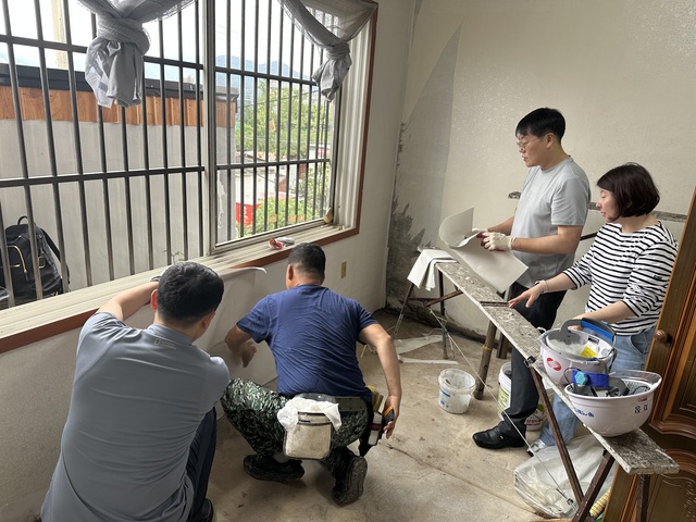 ▲ 신박한 에너지정리' 26호 가구에 한국동서발전과 에너지공단 임직원들이 도배작업을 하는 모습. ⓒ동서발전 제공