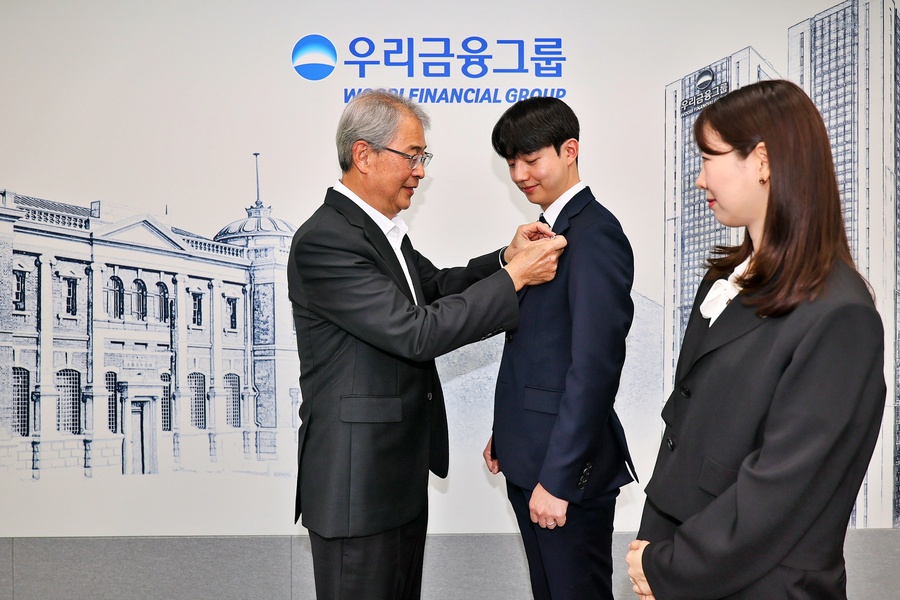 ▲ 임종룡 우리금융 회장이 그룹의 새 가족이 된 동양생명·ABL생명 직원에게 디지털 선도의 의미가 담긴 새로운 그룹 보조휘장을 달아주고 있다.ⓒ우리금융
