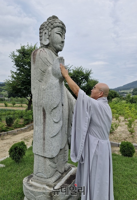 ▲ 현진 스님이 정원에 건립된 '걱정을 가져가고 행복을 얀겨주는 부처님'인 걱정상 에 걱정을 전달하는 방법을 시연해 보이고 있다.ⓒ양승갑 기자