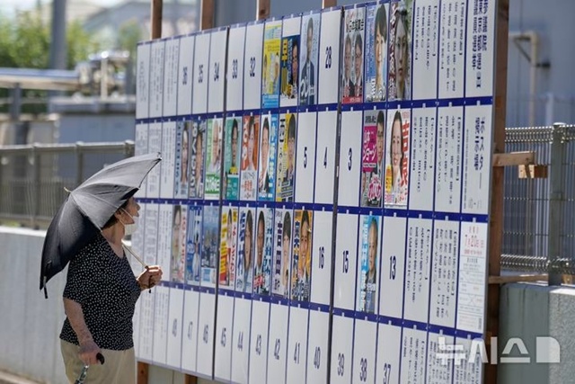 ▲ 일본 도쿄의 한 투표소 인근에서 한 유권자가 참의원 선거 게시판을 보고 있다. 250720 AP/뉴시스. ⓒ뉴시스