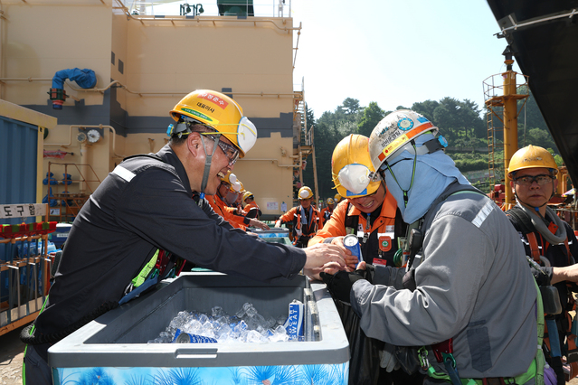 ▲ 한화오션 김희철 대표(왼쪽)가 거제사업장 1도크 주변에서 근로자들에게 시원한 음료를 건네주고 있다. ⓒ한화오션