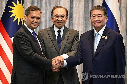 ▲ 28일(현지시간) 말레이시아 쿠알라룸푸르에서 훈 마네트 캄보디아 총리(왼쪽)와 태국 총리 권한대행인 품탐 웨차야차이 부총리 겸 내무부 장관(오른쪽)이 휴전에 합의한 뒤 회담을 중재한 안와르 이브라힘 말레이시아 총리(가운데)와 함께 손을 잡고 있다. /AP/연합뉴스
