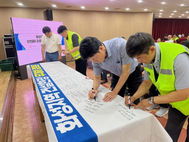 ▲ 화성시 관내 공사현장 관계자 및 안전관리자들이 무재해 결의대회에서 무재해 결의문 현수막에 안전기원 문구를 적고 있다ⓒ화성시 제공