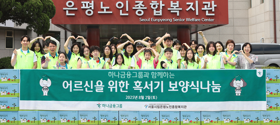 ▲ 하나금융은 지난 2일 서울 은평구에 위치한 서울시립은평노인종합복지관에서 어르신들의 건강한 여름나기를 지원하는 '혹서기 보양식 나눔' 봉사활동을 실시했다. 이날 봉사활동에 참여한 하나금융 임직원과 임직원 가족들이 기념촬영을 하고 있다.ⓒ하나금융