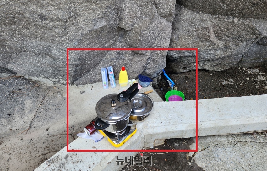 ▲ 천연 암반수가 흘러나와 관광객들이 목을 축이기도 하는 이곳에 식기도구와 설거지 용품이 자리잡고 있다.ⓒ뉴데일리