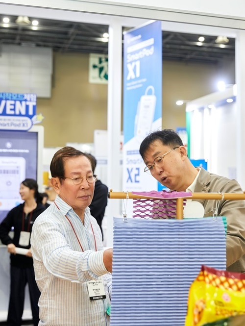 ▲ 지난해 4월24일 킨텍스 전시장을 찾은 교촌그룹 권원강 회장(사진 왼쪽)이 케이앤엘팩 김범진 대표(오른쪽)로부터 ‘바스락’ 종이 완충재의 기능에 대한 설명을 듣고 있다.ⓒ교촌에프앤비