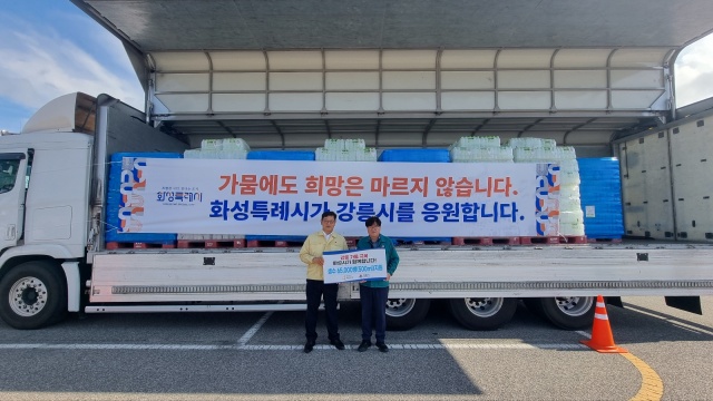 ▲ 김기두 화성시 안전건설국장이 김동율 강릉시 안전국장에게 생수를 전달한 후 기념촬영을 하고 있다ⓒ화성시 제공