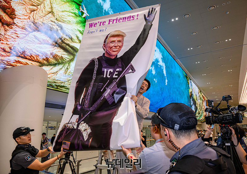 ▲ 미국 이민당국에 의해 체포·구금됐다 풀려난 한국인 316명이 탑승한 전세기가 인천국제공항 2터미널에 도착한 12일 이제석 이제석광고연구소 대표가 공항 입국장에서 트럼프 미국 대통령의 모습이 담긴 플래카드 퍼포먼스를 벌이고 있다.ⓒ인천=서성진 기자