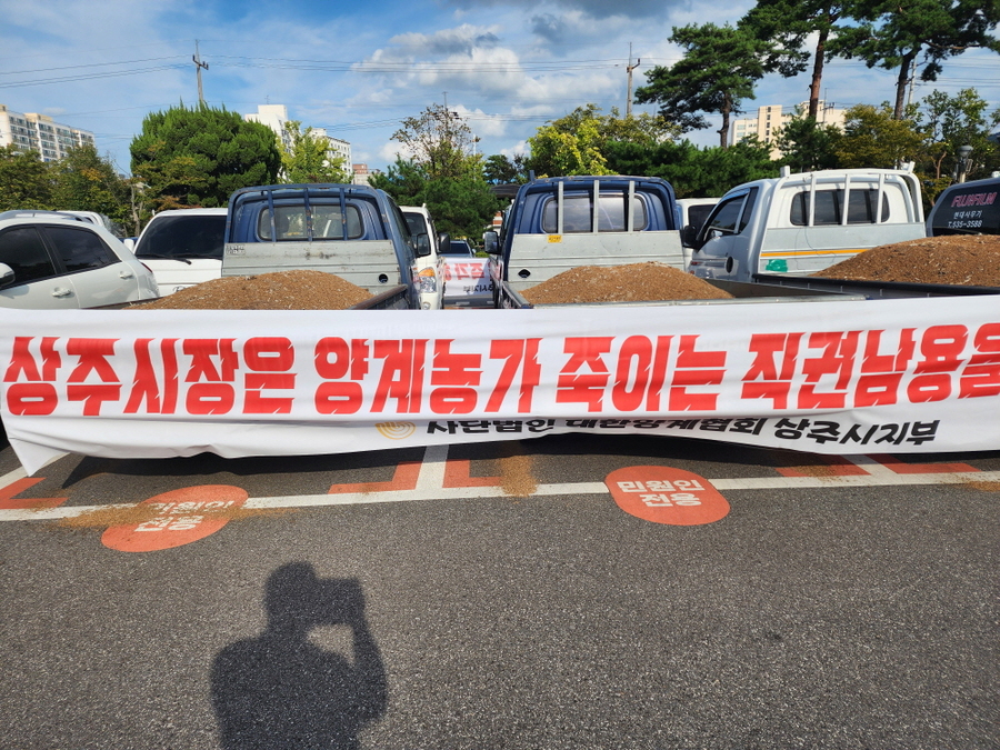 ▲ 상주지역 양계농들이 화물차량에 상주시를 비난하는 현수막을 게재한체 시청주차장을 장기 점거하고 있다ⓒ