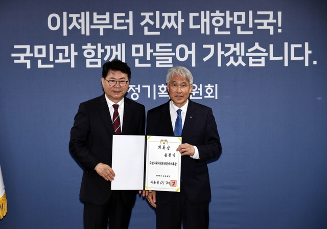 ▲ 이한주(왼쪽) 국정기획위원회 위원장이 지난 6월 16일 서울 종로구 정부서울청사 창성동 별관에서 열린 출범식에서 외교안보분과장을 맡은 홍현익 세종연구소 명예연구위원에게 위촉장을 수여한 뒤 기념촬영을 하고 있다. 이재명 정부의 대통령직인수위원회 역할을 하는 국정기획위에서는 100대 국정과제를 정리하고 과제별로 추진 시점과 목표 등을 정해 '국정운영 5개년 계획'을 마련했다. ⓒ공동취재/뉴시스