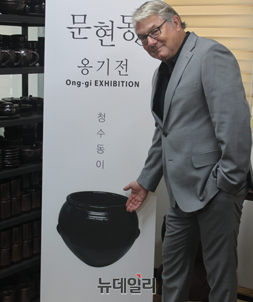 ▲ 세계적인 작가 셰인 구포그가 본정에서 문현동 전시장에서 옹기 그림을 배경으로 포즈를 취하고 있다.ⓒ이길표 기자