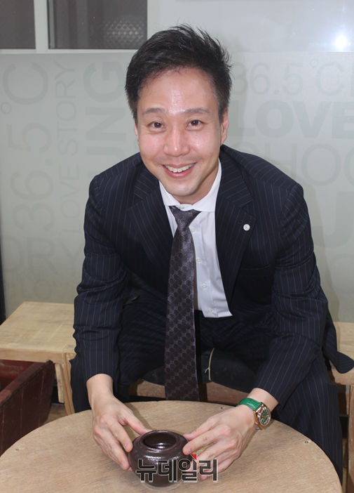 ▲ 장준현 미국 뉴욕주 변호사가 청주 본정 문현동 옹기 전시장에서 옹기 제작과정에 관해 설명을 들은 뒤 100년이 넘는 물레 위에서 기념 사진을 찍고 있다.ⓒ이길표 기자