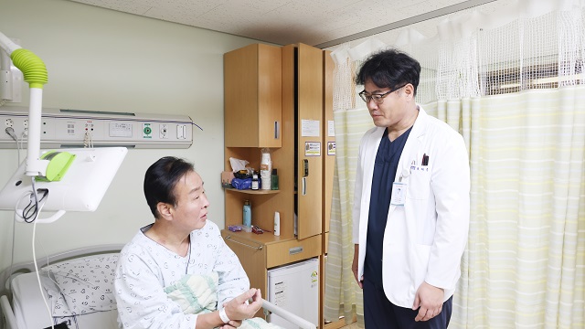 ▲ 세명기독병원 지역심뇌혈관질환센터 조재훈 부장(사진 오른쪽)이 뇌경색 진단 후 혈전제거술을 받고 후유증 없이 회복 중인 A씨를 회진하고 있다.ⓒ세명기독병원