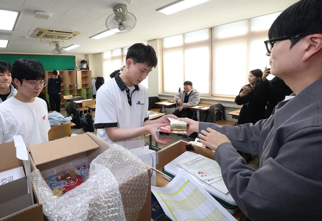 ▲ 경기 수원시에 위치한 수성고등학교 3학년 학생들이 12일 담임교사로부터 수험표와 간식을 건네 받고 있다. ⓒ경기도교육청 제공