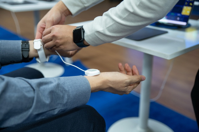 ▲ 한 참관객이 AF Summit 2025에서 열린 대웅제약 '디지털 헬스존'에서 웨어러블 심전도 기기를 착용해 보고 있다. ⓒ대웅제약