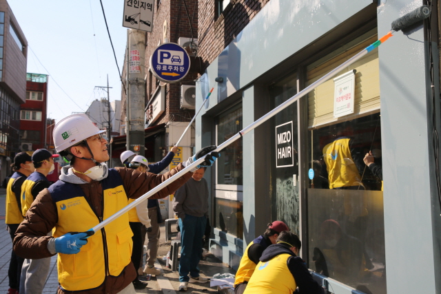 ▲ 한화 건설부문과 서울특별시 기술교육원 동부캠퍼스 교육생들이 노후점포 외벽 도색작업을 하고 있다. ⓒ한화 건설부문