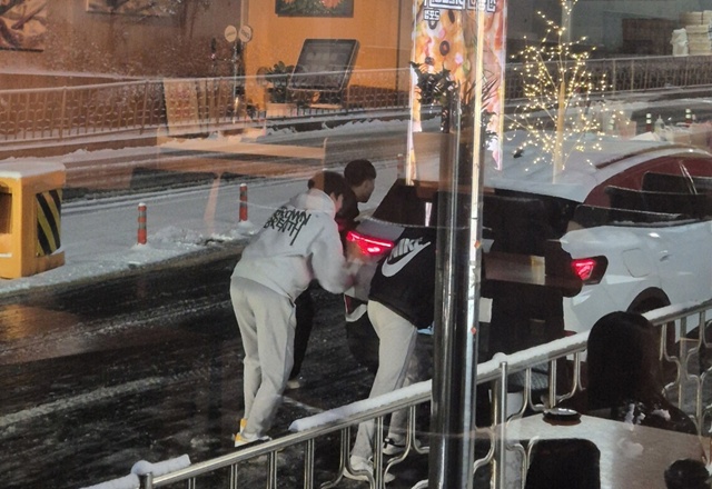 ▲ 폭설이 내린 지난 4일 군포 당동중학교 학생들이 눈길에 고립된 차를 밀고 있다. ⓒ군포시 제공