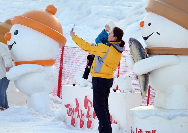 ▲ 25일 휴일을 맞아 강추위에도 불구하고 강원도 평창군 진부면 오대천 일원에 열린 평창송어축제를 찾은 방문객이 눈조각을 배경으로 기념사진을 촬영하고 있다. ⓒ평창관광문화재단