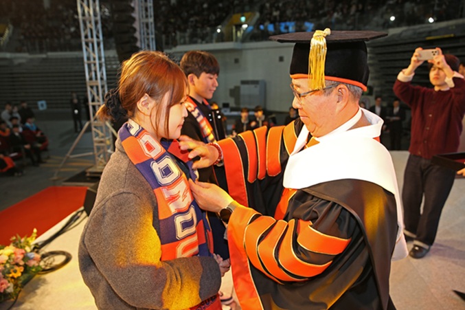 ▲ 윤재웅 총장(오른쪽)이 신입생에게 배지를 달아주고 있다.ⓒ동국대