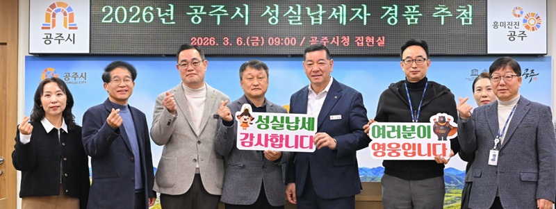 ▲ 지난 6일 공주시청 집현실에서 열린 ‘2026년 공주시 성실납세자 경품 추첨’ 행사에서 최원철 공주시장과 관계자들이 성실납세자 감사 메시지를 들고 기념촬영을 하고 있다.ⓒ공주시