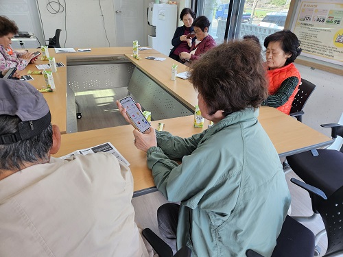 ▲ 증평 AI시니어 안심케어 시범사업에 참여한 어르신들이 휴대폰에서 어플 작동법을 익히고 있다.