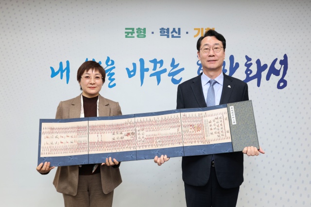 ▲ 정명근 시장과 샤오간시 대표단장이 기념품인 ‘정조대왕 화첩’을 들고 기념촬영을 하고 있다ⓒ화성시 제공