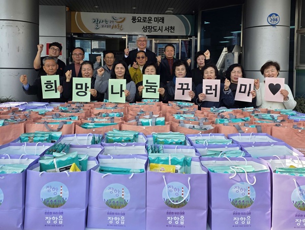 ▲ 장항읍지역사회보장협의체 위원들과 관계자들이 ‘희망나눔꾸러미 지원사업’을 통해 마련한 생필품 꾸러미를 앞에 두고 기념촬영을 하고 있다.ⓒ서천군