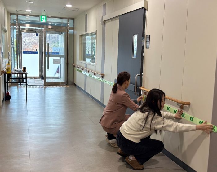 ▲ 실내 복도 벽면에 축광패치 비상대피 유도표지를 관계자들이 직접 설치하고 있다.ⓒ세종시