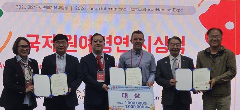 ▲ 2026 태안국제원예치유박람회 국제원예경연대회 시상식에서 충남도 농업기술원 관계자들이 국화 신품종 ‘엔젤루팡’ 대상 수상을 기념해 상장과 상금을 들고 기념촬영을 하고 있다.ⓒ충남도