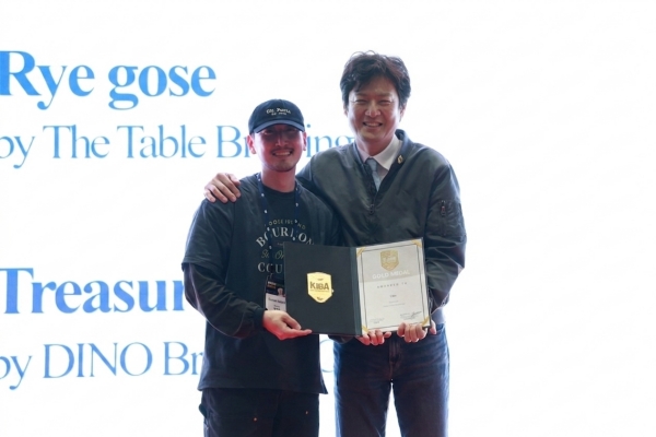 ▲ ‘대한민국 국제 맥주 대회(KIBA 2026)’ 시상식에서 장현준 구스아일랜드 양조사(왼쪽)와 윤정훈 KIBA 조직위원장(오른쪽)이 수상 후 기념촬영을 하고 있다. ⓒ오비맥주