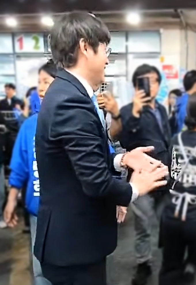▲ 부산 북구갑 보궐선거 출마를 공식화한 하정우 전 청와대 수석이 지난 29일 부산 구포시장 방문 도중 상인과 악수한 직후 손을 털어내고 있는 모습. ⓒ유튜브 '황기자TV' 캡쳐