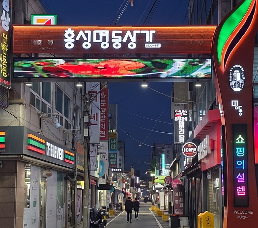 ▲ 홍성명동상가 진입로에 새롭게 설치된 게이트형 LED 전광판 조형물이 화려한 야간 경관을 연출하며 방문객들의 눈길을 끌고 있다.ⓒ홍성군