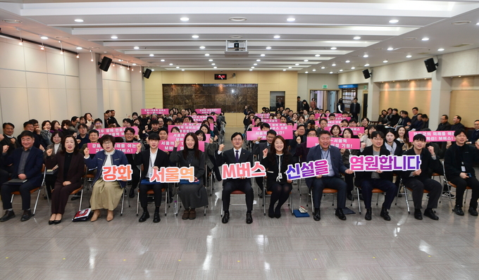 ▲ 강화군 공직자들이 지난  2월 ‘강화~서울역 M버스 유치 결의대회’에서 피켓을 들고 기념촬영을 하고 있다. ⓒ 인천 강화군 제공