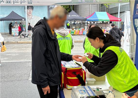 ▲ 제22회 안산국제거리극축제에 마련된 사랑의병원 건강 부스에서 병원 관계자들이 시민들에게 혈압 및 혈당체크를 진행하고 있다. ⓒ사랑의병원 제공