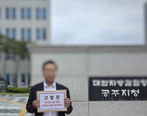 ▲ 김정섭 더불어민주당 공주시장 후보 측 관계자가 검찰청 앞에서 여론조사 왜곡공표 혐의와 관련한 고발장을 들어 보이고 있다.ⓒ선거 캠프