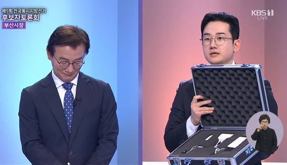 ▲ 정이한 개혁신당 후보가 26일 열린 부산시장 후보 TV토론에서 미국산 경찰용 거짓말탐지기를 들어 보이며 전재수 후보의 시계 의혹 해명을 요구하고 있다.ⓒKBS 부산 방송 캡쳐