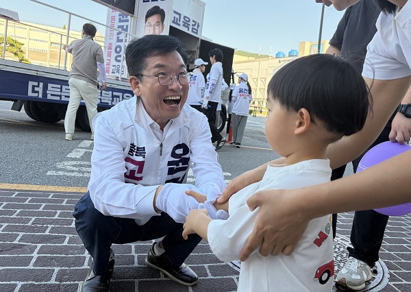 ▲ 윤건영 충북도교육감 후보가 1일 거리유세중 만난 아이의 손을 맞잡고 환하게 웃고 있다.ⓒ윤건영 후보 캠프 제공