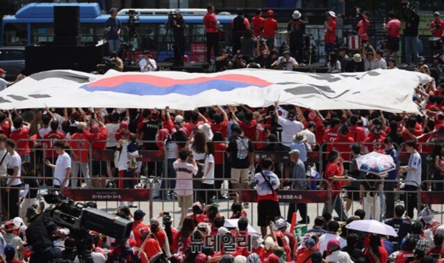 ▲ 2026 북중미 월드컵 A조 1차전 한국과 체코의 경기가 열린 12일 오전 서울 광화문광장에서 열린 응원전에서 애국가가 나오자 대형 태극기가 펼쳐지고 있다. ⓒ뉴데일리