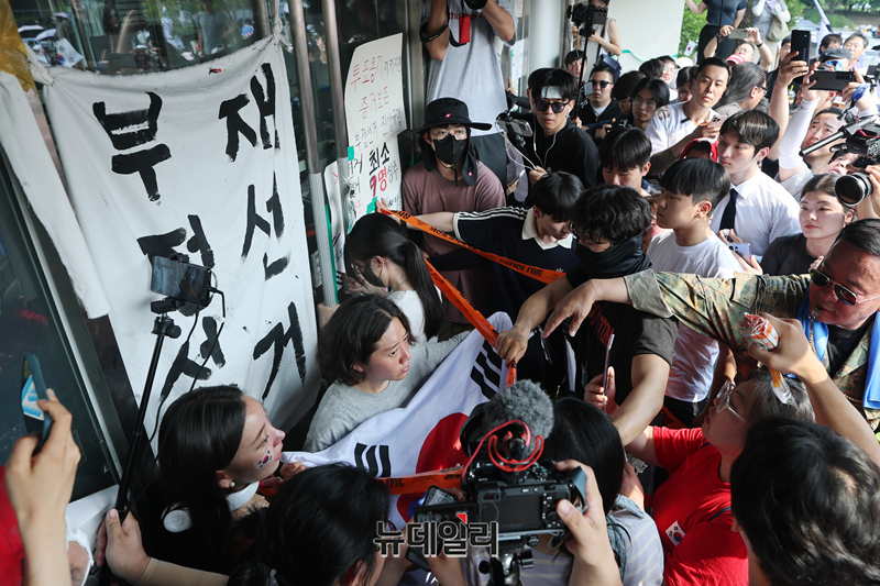 ▲ 6·3지방선거 투표용지 부족 사태로 촉발된 잠실 개표소 봉쇄 시위가 12일째 이어진 16일 서울 송파구 올림픽공원 핸드볼경기장 개표소 앞에서 한 시민이 국민의힘과 대한체육회 관계자들의 진입을 봉쇄하기 위해 문을 잡고 있다. ⓒ정상윤 기자