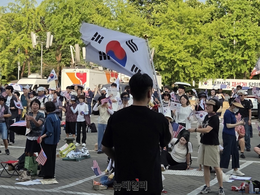 ▲ 18일 오후 서울 송파구 올림픽공원 핸드볼경기장 일대에서 한 시민이 집회에 참가해 태극기를 흔들고 있다. ⓒ노유지 기자