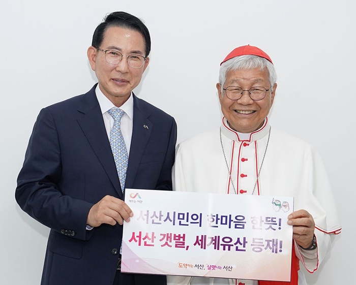 ▲ 이완섭 서산시장(왼쪽)과 유흥식 추기경이 12일 해미국제성지에서 가로림만 서산갯벌의 세계자연유산 등재를 기원하는 홍보판을 함께 들어 보이며 기념촬영을 하고 있다.ⓒ서산시