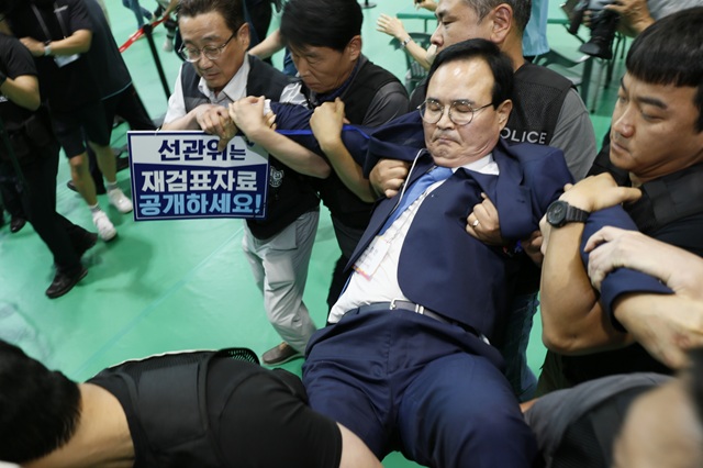 ▲ 15일 충북 충주 교통대 체육관 충주시장 재검표 개표장에서 민주당 맹정섭 전 충주시장 후보가 강제 퇴거 당하고 있다. ⓒ뉴시스