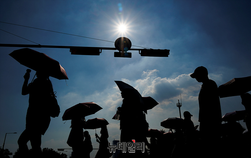 ▲ 지난해 7월 서울 송파구 종합운동장 사거리에서 시민들이 양산을 쓴 채 발걸음을 재촉하고 있다. ⓒ서성진 기자